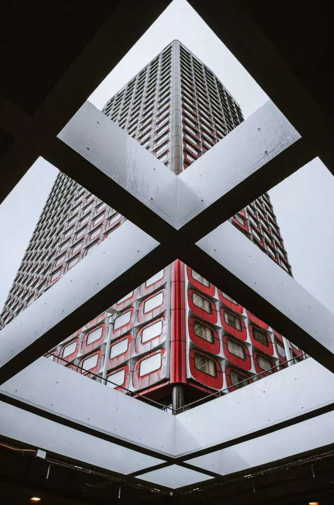 Contemporary high-rise apartment tower with a striking geometric facade viewed from below.